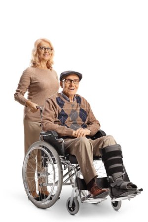 Téléchargez les photos : Homme avec une attelle de jambe assis dans un fauteuil roulant avec une femme derrière lui isolé sur fond blanc - en image libre de droit