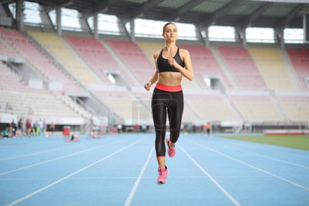 Téléchargez les photos : Athlète féminine qui court sur une piste dans une arène sportive - en image libre de droit