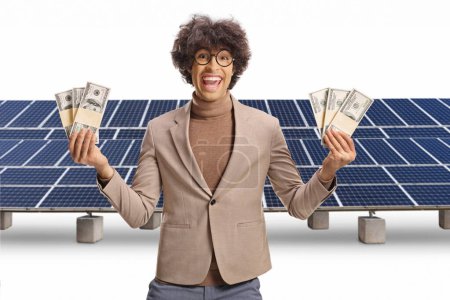 Foto de Joven emocionado sosteniendo dinero frente a paneles solares aislados sobre fondo blanco - Imagen libre de derechos