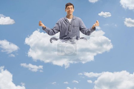 Téléchargez les photos : Homme en pyjama et pratiquant le yoga sur un nuage dans le ciel - en image libre de droit