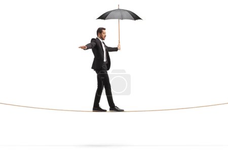 Foto de Foto de perfil completo de un hombre de negocios con un paraguas caminando sobre una cuerda aislada sobre fondo blanco - Imagen libre de derechos