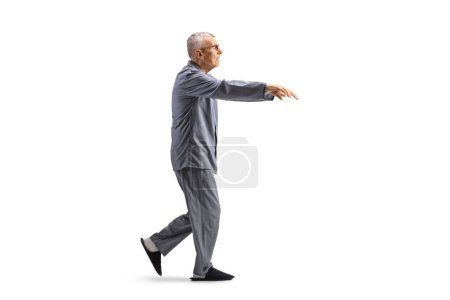Photo for Full length profile shot of a senior man in pajamas sleepwalking isolated on white background - Royalty Free Image