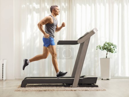 Photo for Fit young man running on a treadmill at home - Royalty Free Image