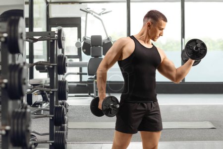 Téléchargez les photos : Homme faisant de l'exercice de musculation dans une salle de gym, sport et fitness concept - en image libre de droit