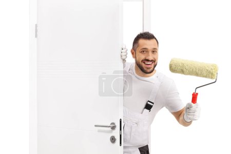 Photo for Painter holding a paint roller and peeking from behind a door - Royalty Free Image