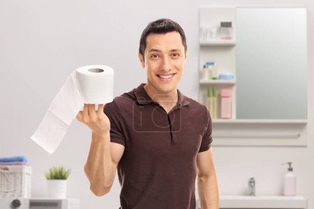 Téléchargez les photos : Un type tenant un rouleau de papier toilette dans une salle de bain - en image libre de droit