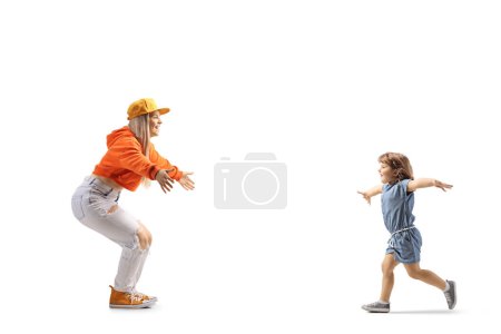 Téléchargez les photos : Plan de profil complet d'une petite fille courant vers une jeune femelle avec les bras grands ouverts isolés sur fond blanc - en image libre de droit