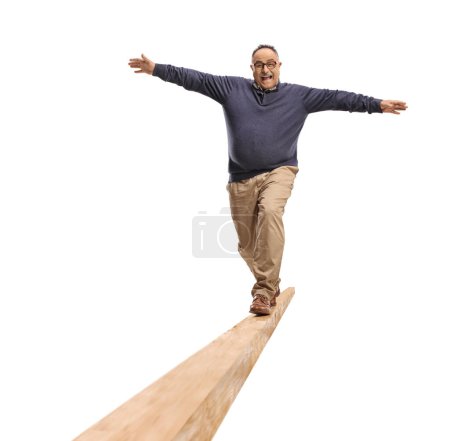 Téléchargez les photos : Portrait complet d'un homme mature marchant sur une poutre en bois isolée sur fond blanc - en image libre de droit