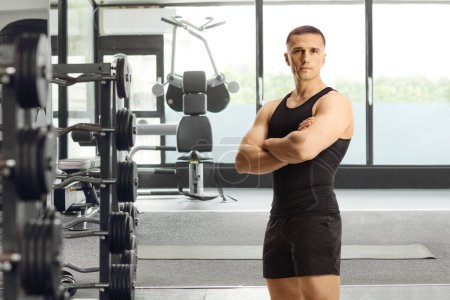 Téléchargez les photos : Coach de remise en forme posant avec les bras croisés dans une salle de gym - en image libre de droit