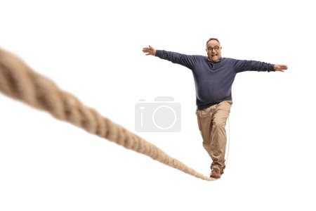 Photo for Full length portrait of a mature man walking on a rope isolated on white background, keep balance concept - Royalty Free Image