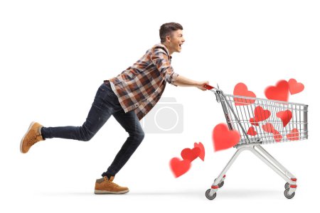 Photo for Young man running with hearts inside a shopping cart isolated on white background - Royalty Free Image