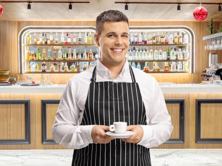 Photo for Waiter holding an espresso coffee and smiling in front of a bar - Royalty Free Image
