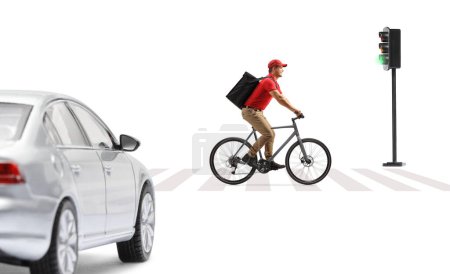 Delivery guy in a red t-shirt delivering food with a bicycle, crossing a road at a pedestrian zebra sign isolated on white background