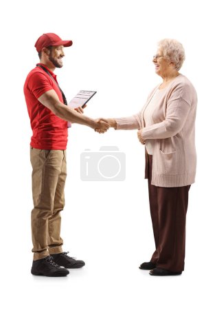 Full length profile shot of courier and an elderly woman shaking hands isolated on white background