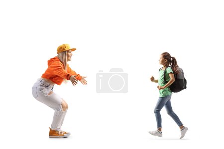 Téléchargez les photos : Plan de profil complet d'une élève femelle courant vers une jeune femelle avec les bras grands ouverts isolés sur fond blanc - en image libre de droit