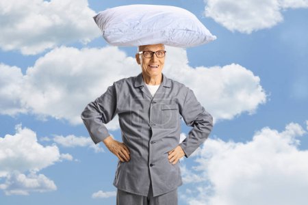 Téléchargez les photos : Homme âgé en pyjama avec oreiller sur la tête, nuages et ciel bleu en arrière-plan - en image libre de droit