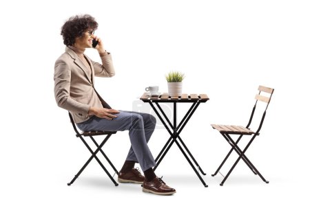 Téléchargez les photos : Plan du profil d'un jeune homme assis dans un café et utilisant un smartphone isolé sur fond blanc - en image libre de droit