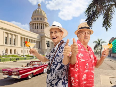 Téléchargez les photos : Touriste homme âgé avec des cocktails gesticulant pouces vers le haut à La Havane, Cuba - en image libre de droit