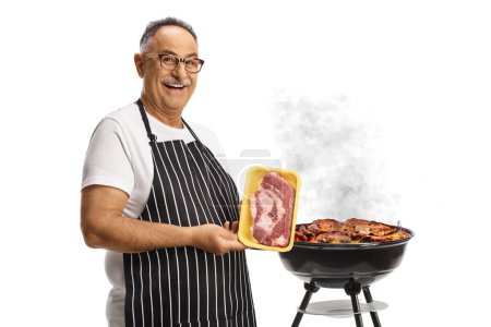 Foto de Hombre sosteniendo un paquete de filete crudo frente a una barbacoa aislada sobre fondo blanco - Imagen libre de derechos