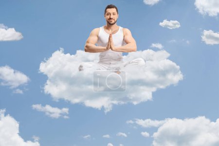 Foto de Ajuste joven en ropa blanca practicando meditación de yoga en el cielo en una nube - Imagen libre de derechos