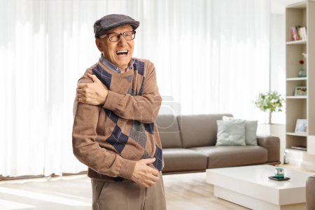 Téléchargez les photos : Homme âgé à la maison souffrant d'une douleur sévère à l'épaule - en image libre de droit