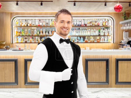 Photo for Professional waiter with a towel around his arm at a hotel bar - Royalty Free Image