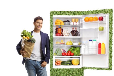 Young man holding a grocery bag and leaning on a green eco-friendly fridge isolated on white background