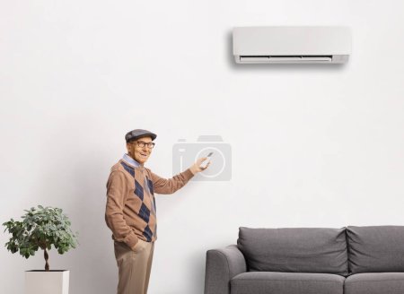 Téléchargez les photos : Homme âgé mettant sur une unité de climatisation à la maison - en image libre de droit