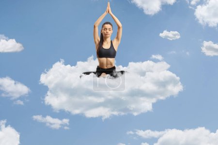 Téléchargez les photos : Jeune femme exerçant le yoga sur un nuage dans le ciel - en image libre de droit