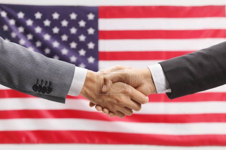 Foto de Empresarios estrechando la mano frente a una bandera de EE.UU. - Imagen libre de derechos
