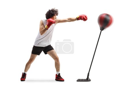Foto de Joven golpeando un soporte con guantes de boxeo aislados sobre fondo blanco - Imagen libre de derechos