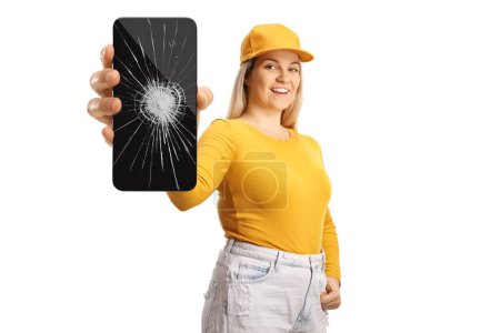 Téléchargez les photos : Adolescente tenant un smartphone avec verre d'écran cassé isolé sur fond blanc - en image libre de droit