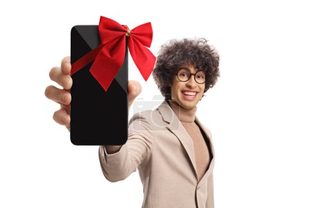 Téléchargez les photos : Jeune homme mignon tenant un smartphone avec arc rouge isolé sur fond blanc - en image libre de droit