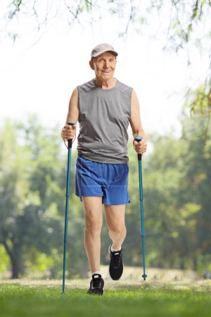 Photo for Elderly man in sportswear walking with trekking poles in nature - Royalty Free Image