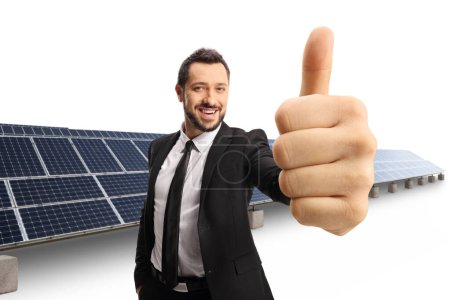 Foto de Feliz hombre de negocios haciendo un gesto de pulgar hacia arriba frente a paneles solares sostenibles aislados sobre fondo blanco - Imagen libre de derechos