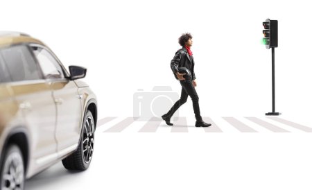 Photo for Young man in leather jacket walking at a pedestrian crossing and carrying a motorbike helmet isolated on white background - Royalty Free Image