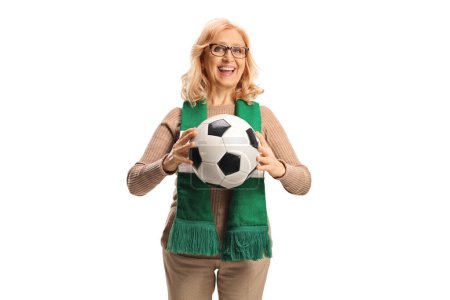 Foto de Mujer de mediana edad sosteniendo un balón de fútbol y sonriendo aislada sobre fondo blanco - Imagen libre de derechos