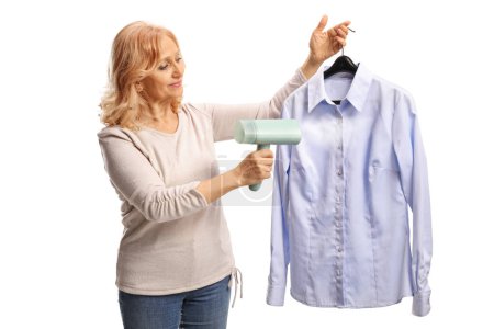 Téléchargez les photos : Femme tenant une chemise sur un cintre et utilisant un fer à vapeur isolé sur fond blanc - en image libre de droit