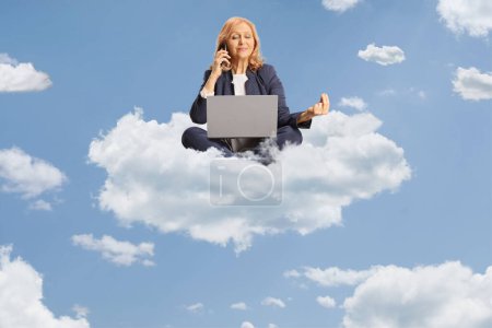 Téléchargez les photos : Femme d'affaires utilisant un ordinateur portable et un smartphone et assise sur un nuage - en image libre de droit