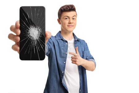 Téléchargez les photos : Homme adolescent tenant un smartphone et pointant vers une fissure d'écran isolé sur fond blanc - en image libre de droit