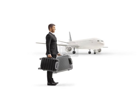 Photo for Full length profile shot of a businessman holding suitcases in front of a plane isolated on white background - Royalty Free Image