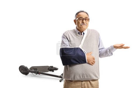 Téléchargez les photos : Homme mûr malheureux avec un bras cassé blessé à partir d'un scooter électrique isolé sur fond blanc - en image libre de droit