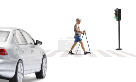 Foto de Foto de perfil completo de un anciano cruzando una calle con bastones de trekking aislados sobre fondo blanco - Imagen libre de derechos