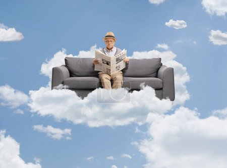 Photo for Elderly man with a newspaper enjoying on a sofa up in the sky on a cloud - Royalty Free Image