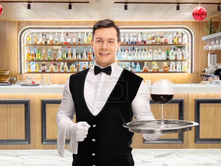 Téléchargez les photos : Serveur tenant un plateau avec un verre de vin rouge dans un bar - en image libre de droit