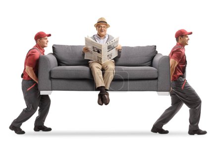 Téléchargez les photos : Déménageurs portant un canapé et un homme âgé assis et lisant un journal isolé sur fond blanc - en image libre de droit