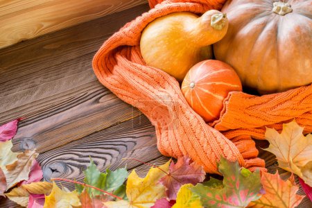 Téléchargez les photos : Citrouilles halloween enveloppé dans un pull orange confortable, feuilles tombées sur table en bois. vue du dessus, espace de copie - en image libre de droit