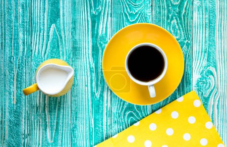 Foto de Taza de té negro en plato amarillo y leche amarilla ju - Imagen libre de derechos