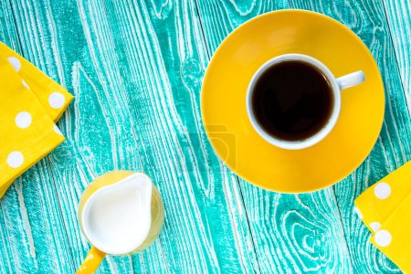 Téléchargez les photos : Tasse de thé noir sur une assiette jaune et du lait jaune ju - en image libre de droit