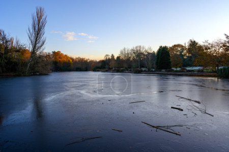 Foto de Un lago congelado al atardecer. Hay hielo en la superficie del lago en esta escena invernal. Un frío día de invierno en Kelsey Park, Beckenham, Kent, Reino Unido. - Imagen libre de derechos